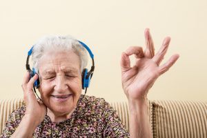 senior woman making okay sign while wearing headphones to listening music